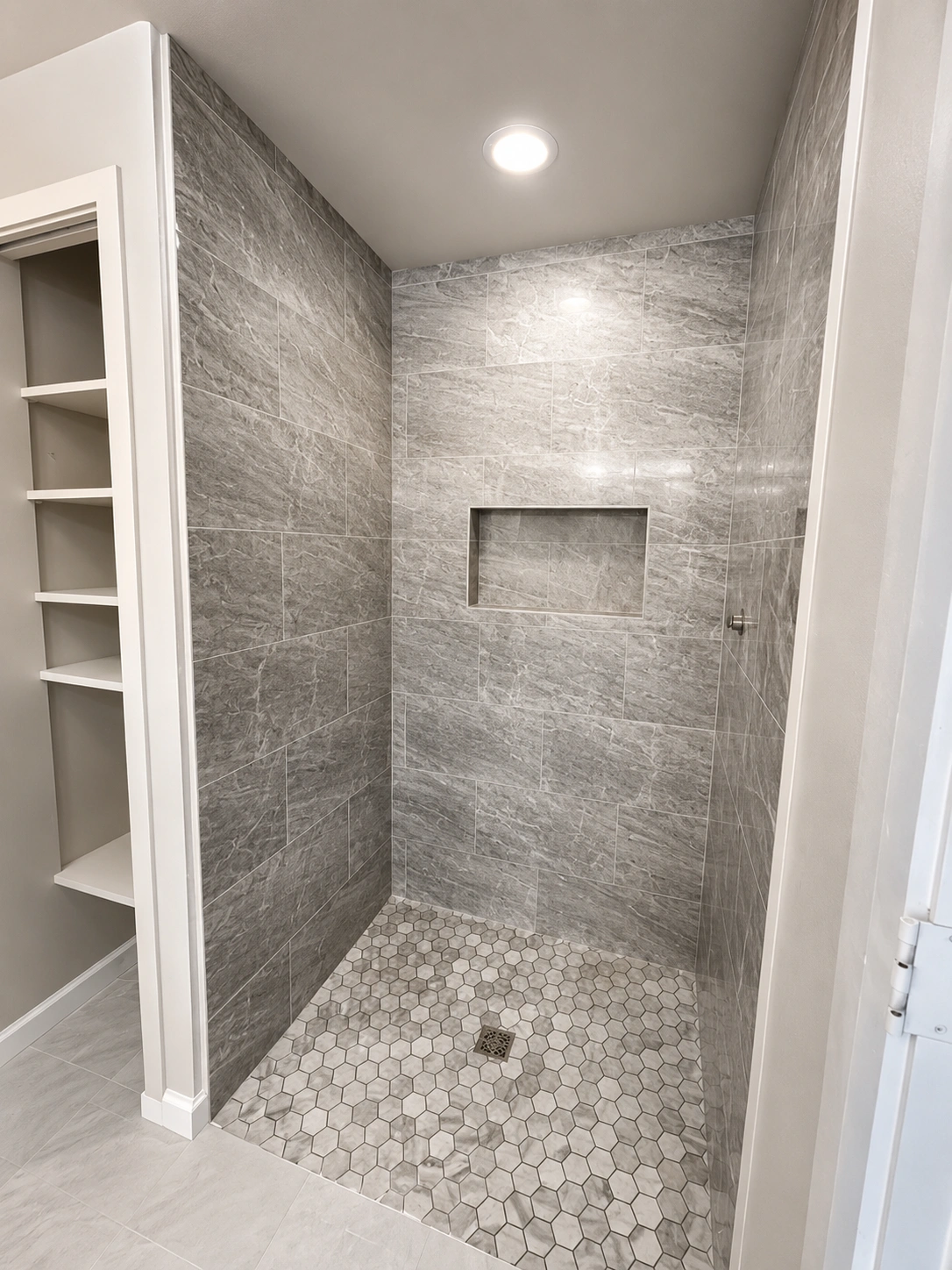 Custom shower featuring grey stone-patterned tiles and hexagonal mosaic floor, showcasing design for Seattle home remodeling projects.